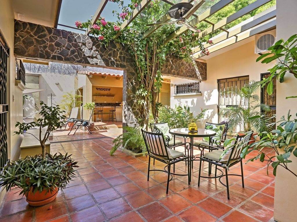 Outdoor patio with terracotta tiles, tropical plants, plunge pool, wet bar, and seating area for dining and relaxation