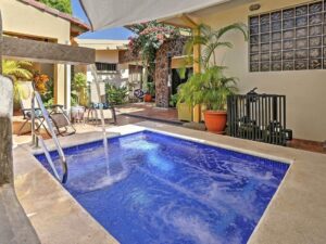 Sparkling plunge pool with water jets, cascade, and underwater seating in a private patio surrounded by tropical vegetation